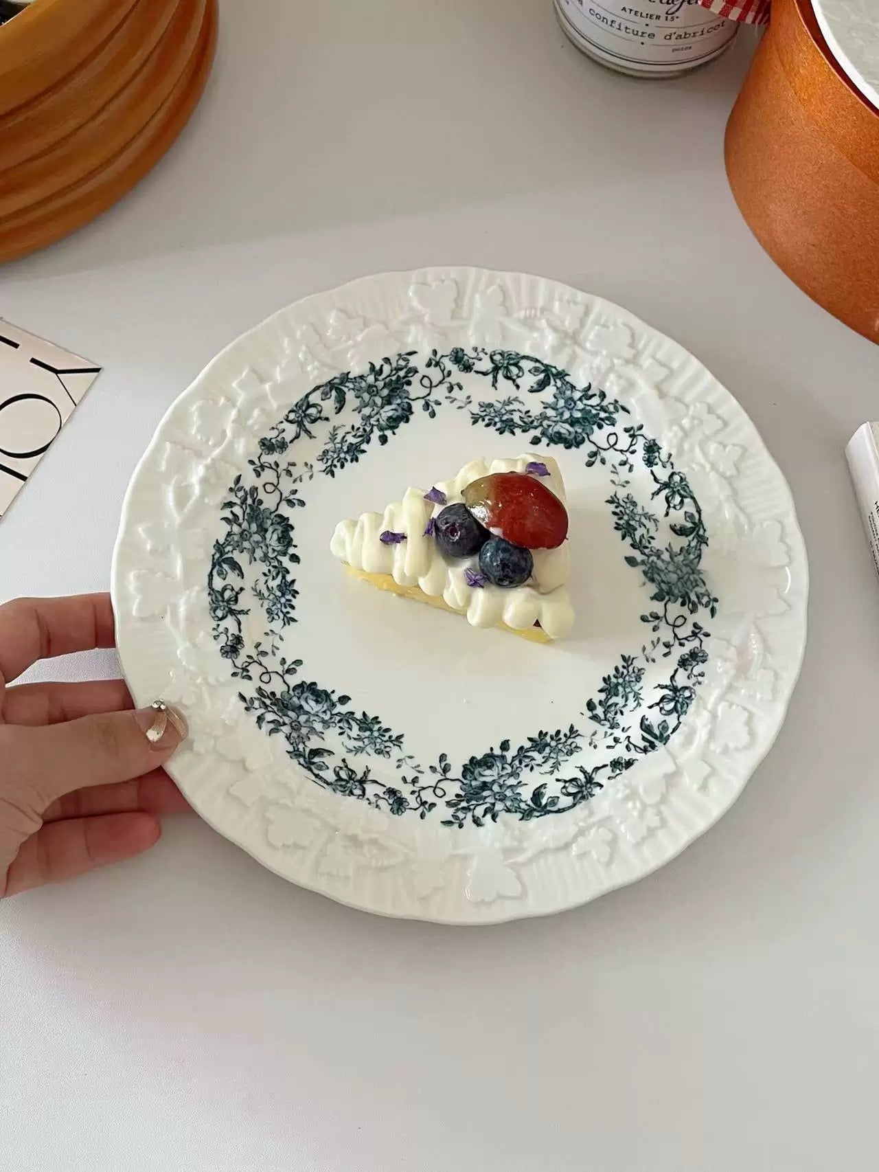 Decorative plate with a small dessert topped with berries on a white surface.