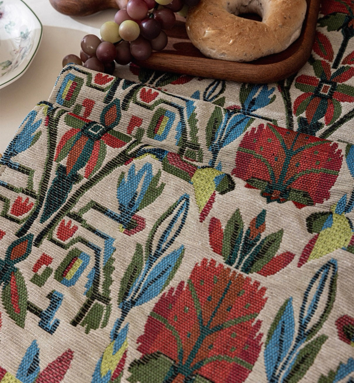 Close-up of a patterned fabric with colorful leaves and flowers on a neutral background.