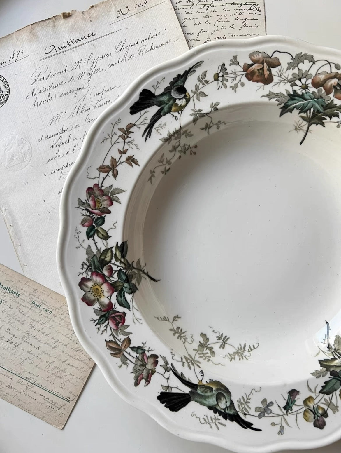 Decorative plate with floral and bird patterns on a surface with handwritten text.