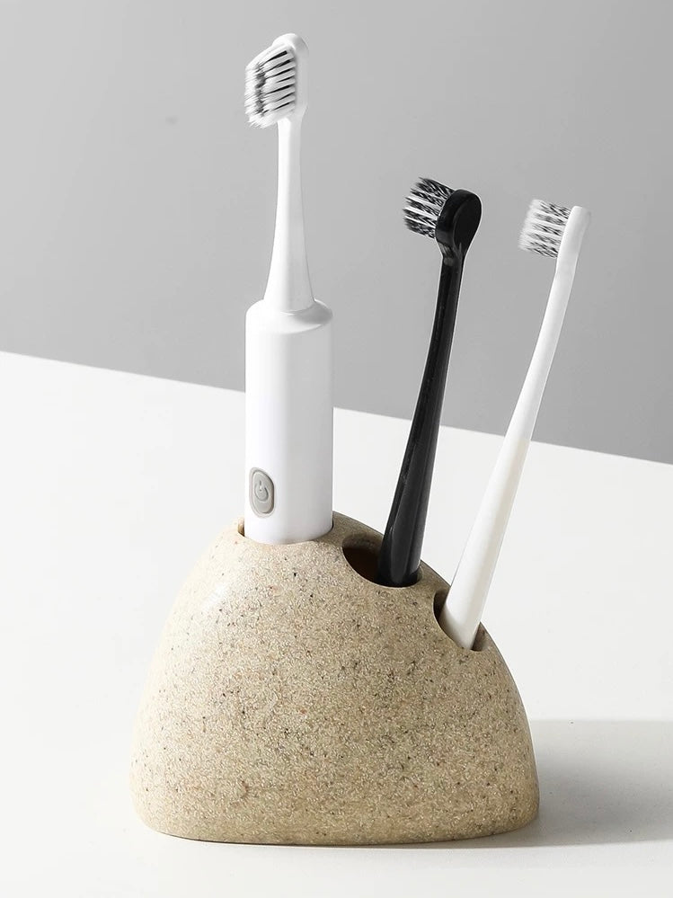 Ceramic toothbrush holder with three toothbrushes on a light gray background