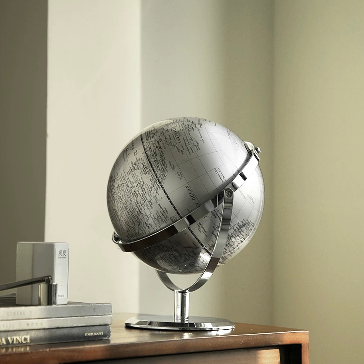 Silver globe on a wooden table with a neutral background