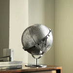 Silver globe on a wooden table with a neutral background
