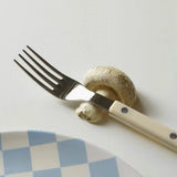 Fork and knife with a mushroom on a white surface
