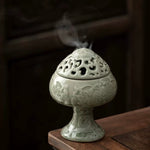 Decorative ceramic incense burner with smoke on a wooden surface