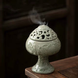 Decorative ceramic incense burner with smoke on a wooden surface
