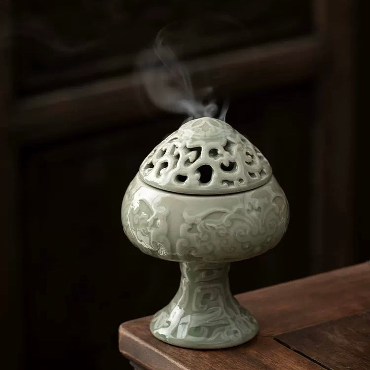 Decorative ceramic incense burner with smoke on a wooden surface