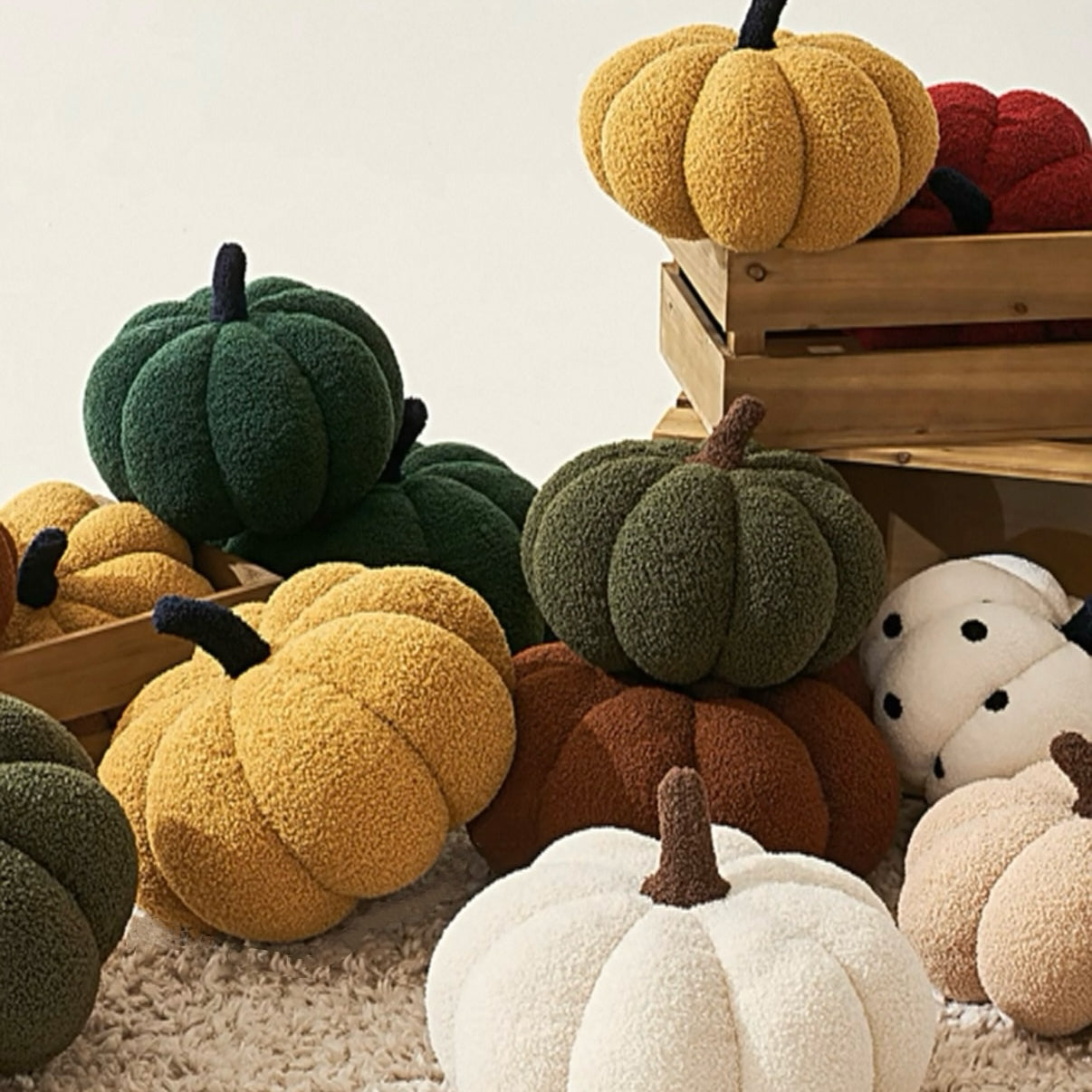 Collection of colorful pumpkin-shaped cushions on a textured surface with a wooden crate in the background.