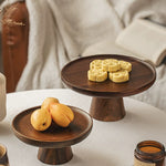 Wooden cake stands with fruits and cookies on a white surface