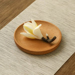 Wooden coaster with a white flower and branch on a textured surface