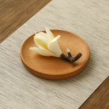Wooden coaster with a white flower and branch on a textured surface