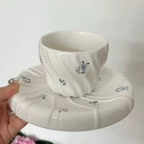 Ceramic cup and saucer with floral design held against a white background