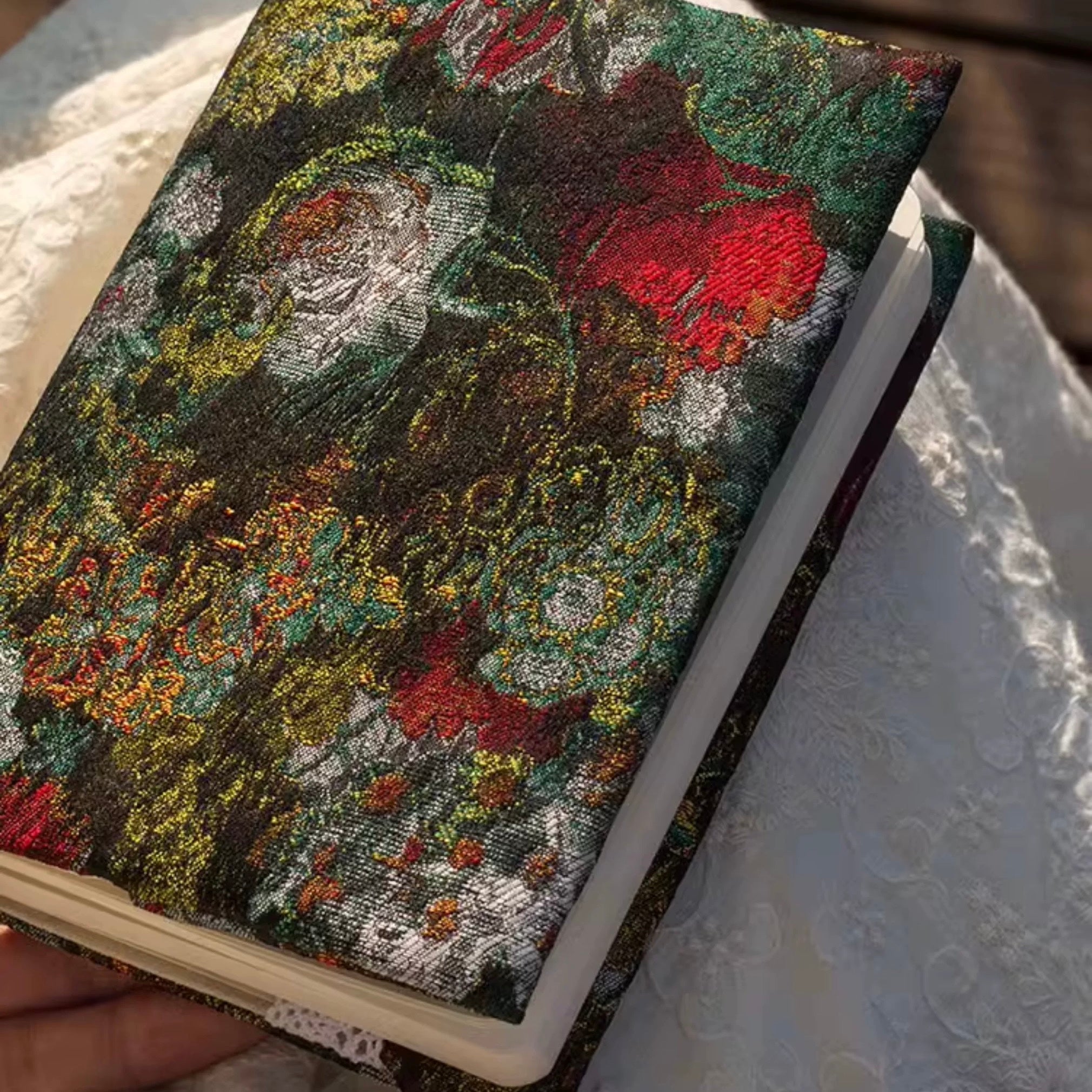 Notebook with a textured floral cover held on a textured surface