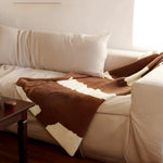 White sofa with brown and white patterned throw blanket in a living room setting.