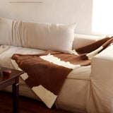 White sofa with brown and white patterned throw blanket in a living room setting.