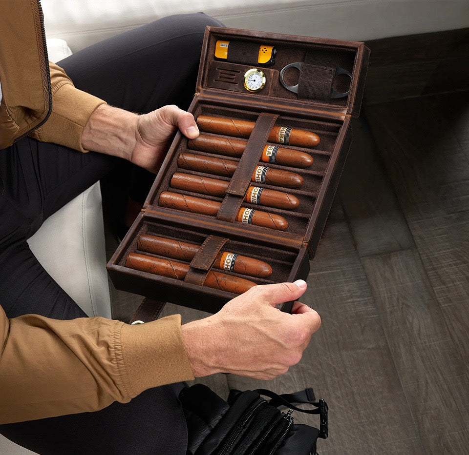 Person holding a wooden humidor with cigars and accessories.