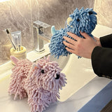 Two fluffy cleaning cloths shaped like sheep on a bathroom counter.