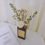 Decorative vase with flowers on a surface next to an open book