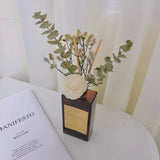 Decorative vase with flowers on a surface next to an open book