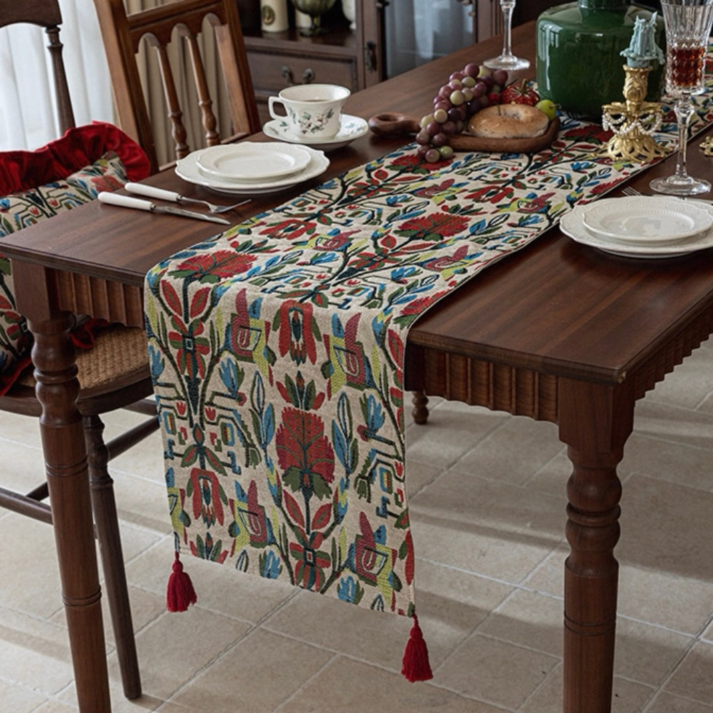 Dining table set with a patterned table runner, plates, and glasses on a wooden table.