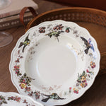 Decorative ceramic plate with floral and bird patterns on a wooden surface.