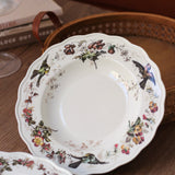 Decorative ceramic plate with floral and bird patterns on a wooden surface.