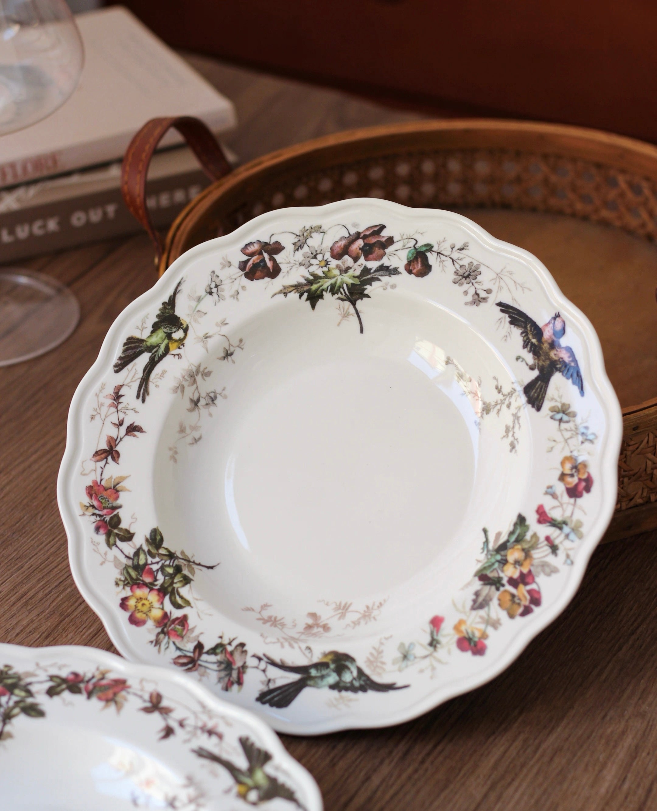 Decorative ceramic plate with floral and bird patterns on a wooden surface.