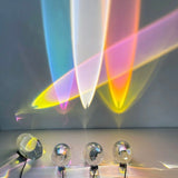 Colorful light beams projected onto a wall with four clear spherical objects below.