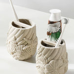 Two ceramic toothbrush holders with beach-themed designs on a white surface.