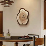 Wooden wall clock on a wall above a dining table with chairs.