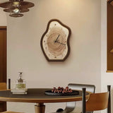 Wooden wall clock on a wall above a dining table with chairs.