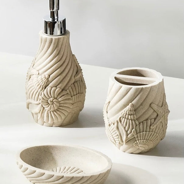 Set of ceramic bathroom accessories with shell designs on a light background