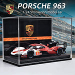 Porsche 963 model car in a display case with Porsche logo.