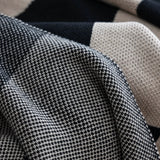 Close-up of a textured fabric with a checkered pattern in black, white, and beige.