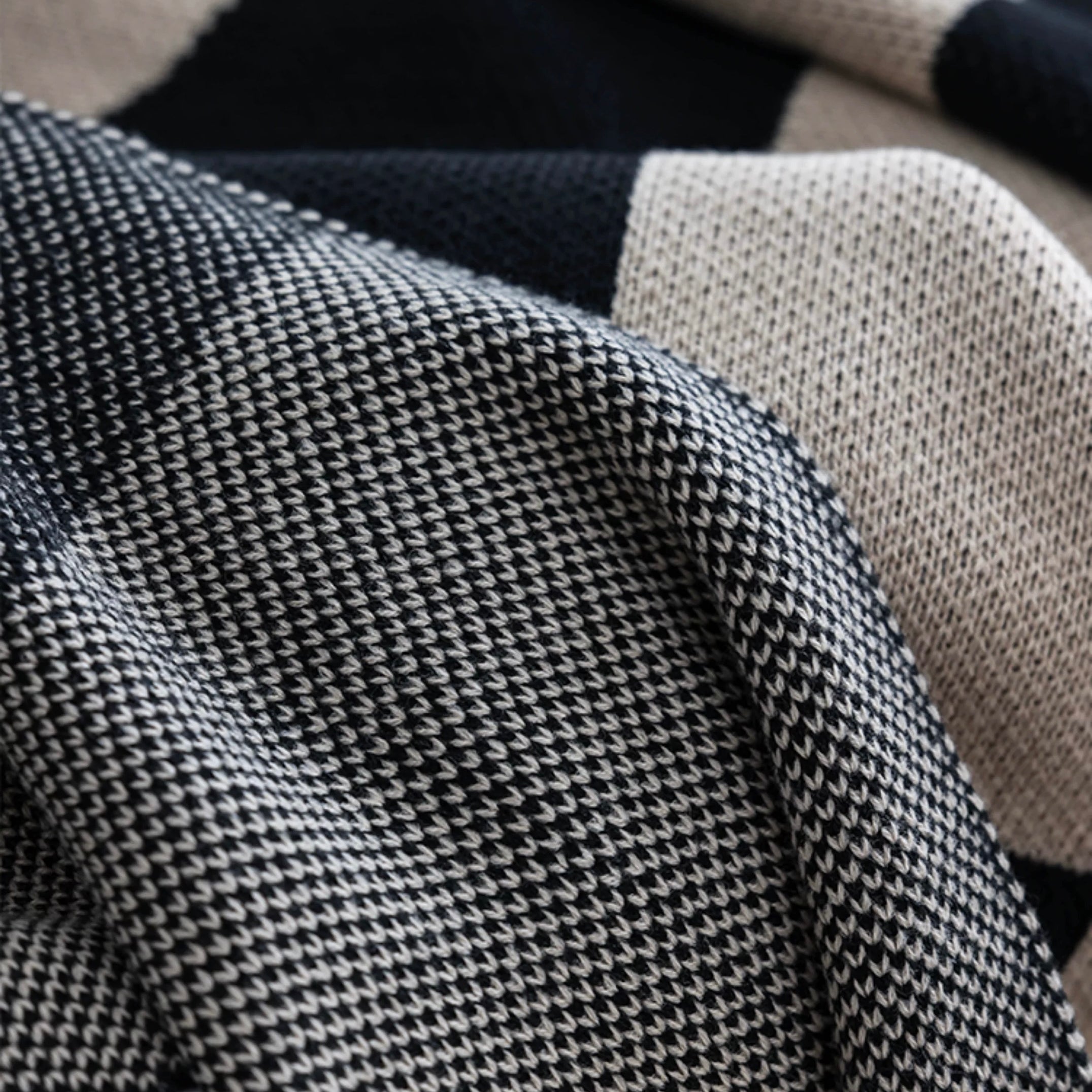 Close-up of a textured fabric with a checkered pattern in black, white, and beige.