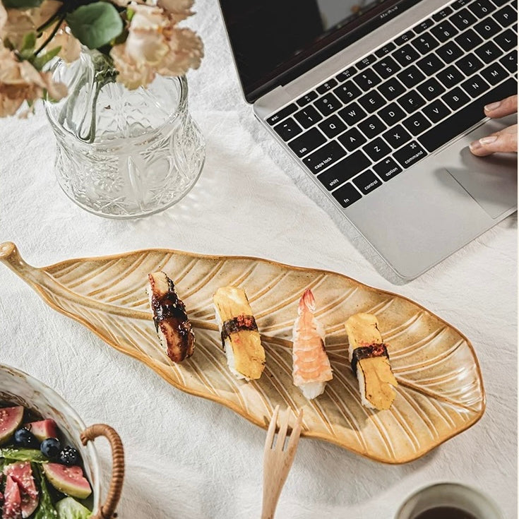 Laptop on a table with sushi, coffee, and flowers