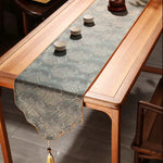 Wooden table with a decorative table runner and small cups on a wooden floor.
