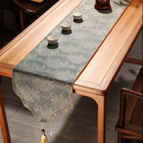 Wooden table with a decorative table runner and small cups on a wooden floor.