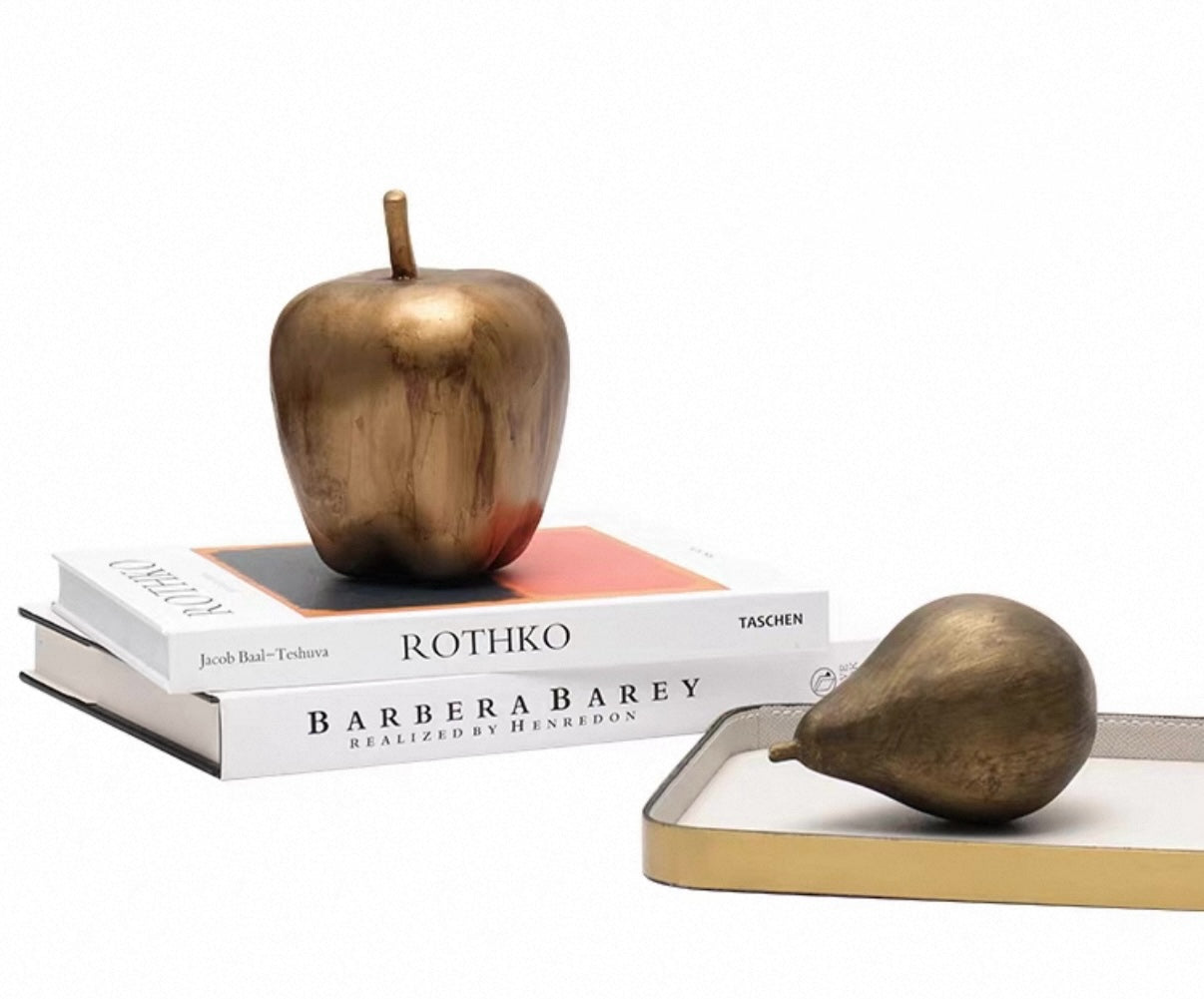 Bronze apple and pear on books with a white background