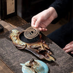 Person lighting incense on a decorative incense burner with intricate designs.