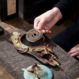 Person lighting incense on a decorative incense burner with intricate designs.