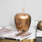 Bronze apple-shaped object on a magazine with a white background