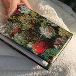 Floral patterned notebook held by a hand on a textured surface