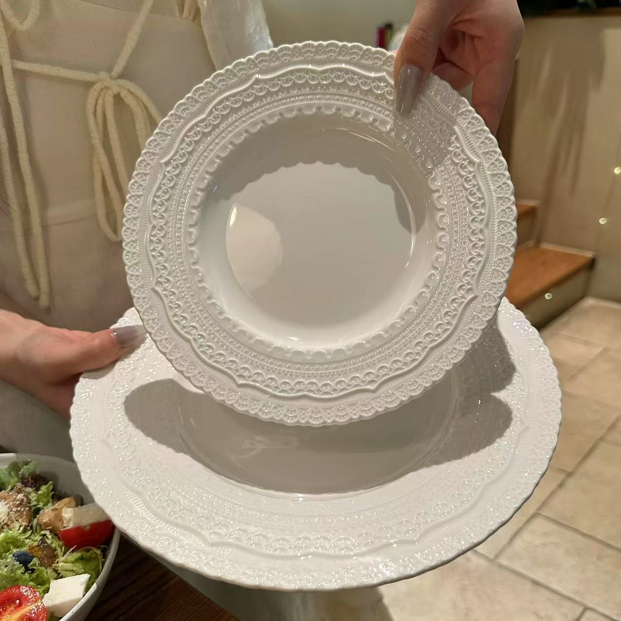 White lace-patterned plate held by a person with a blurred background
