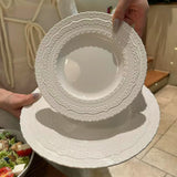 White lace-patterned plate held by a person with a blurred background