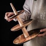 Person holding a wooden tiered stand with a dark background