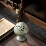Ceramic incense burner on a textured surface with a blurred background