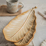 Ceramic leaf-shaped platter and mug on a textured surface
