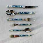 Set of floral-patterned cutlery on a white fabric background