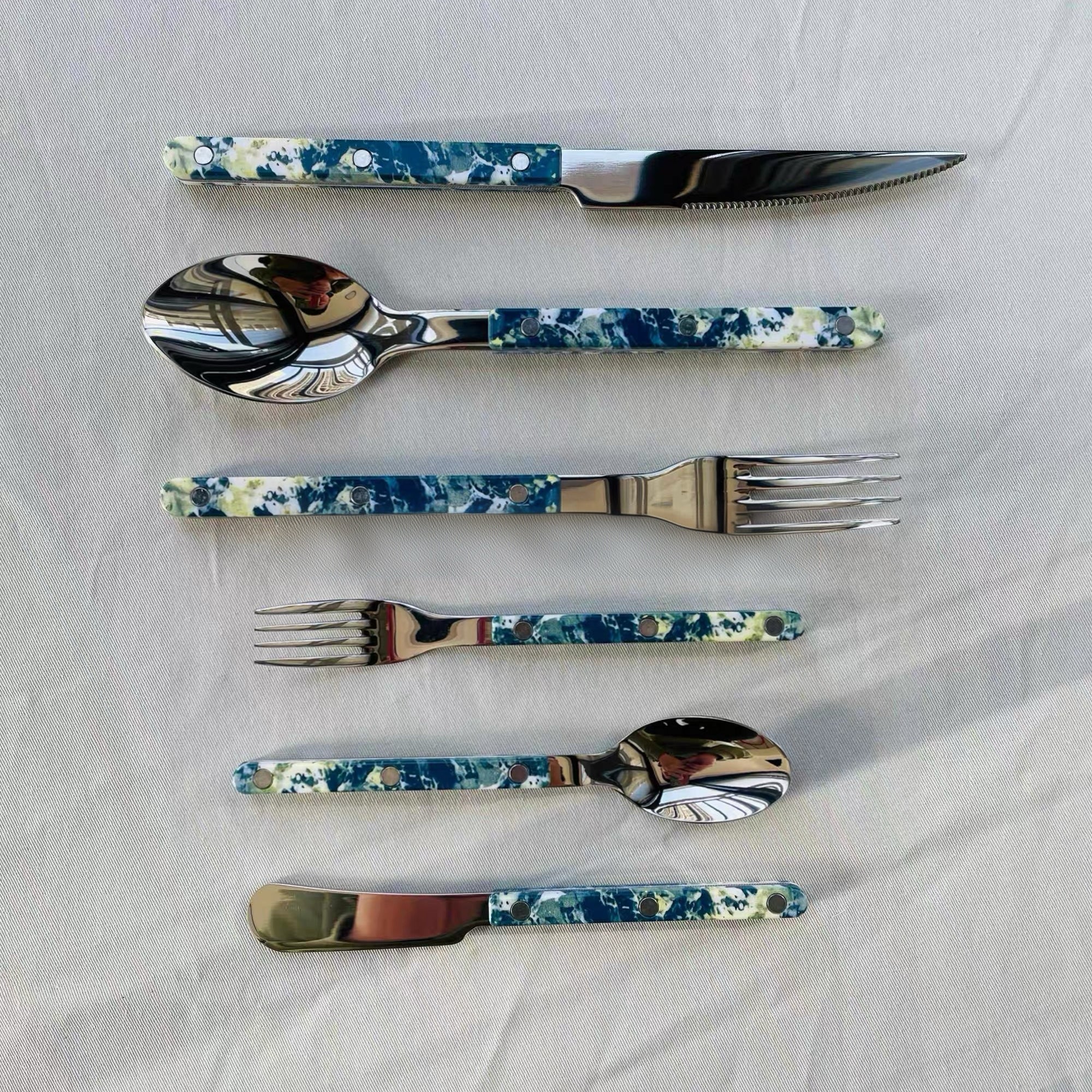 Set of floral-patterned cutlery on a white fabric background