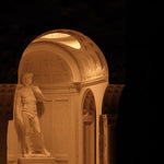 Statue of a man in a classical architectural setting with a dark background
